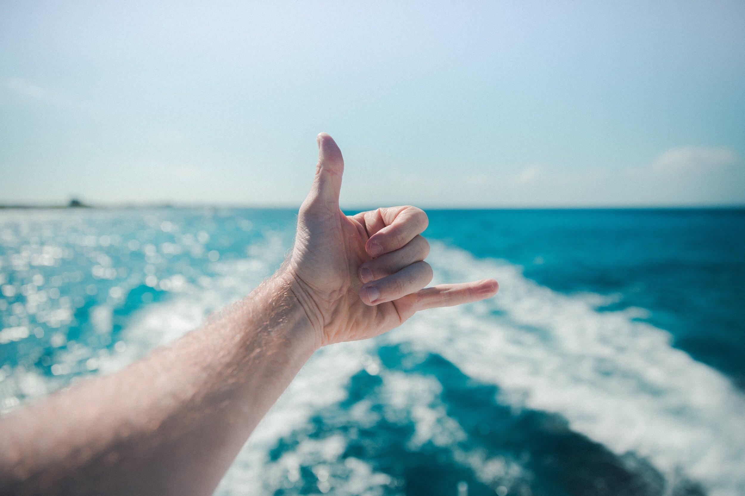 Hand making shaka sign over ocean waves